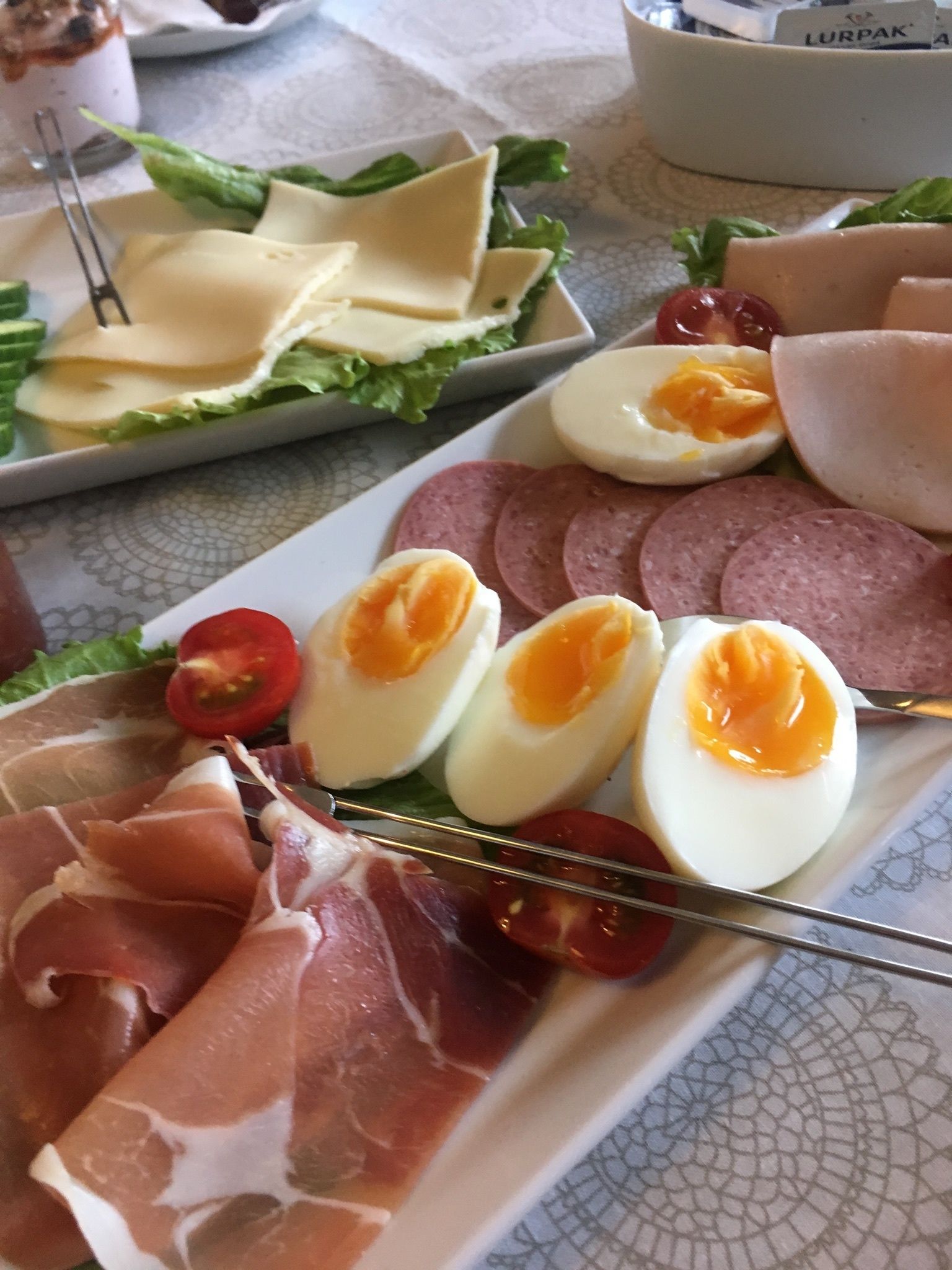 Un plato con salami en rodajas, prosciutto, huevos duros y tomates cherry.