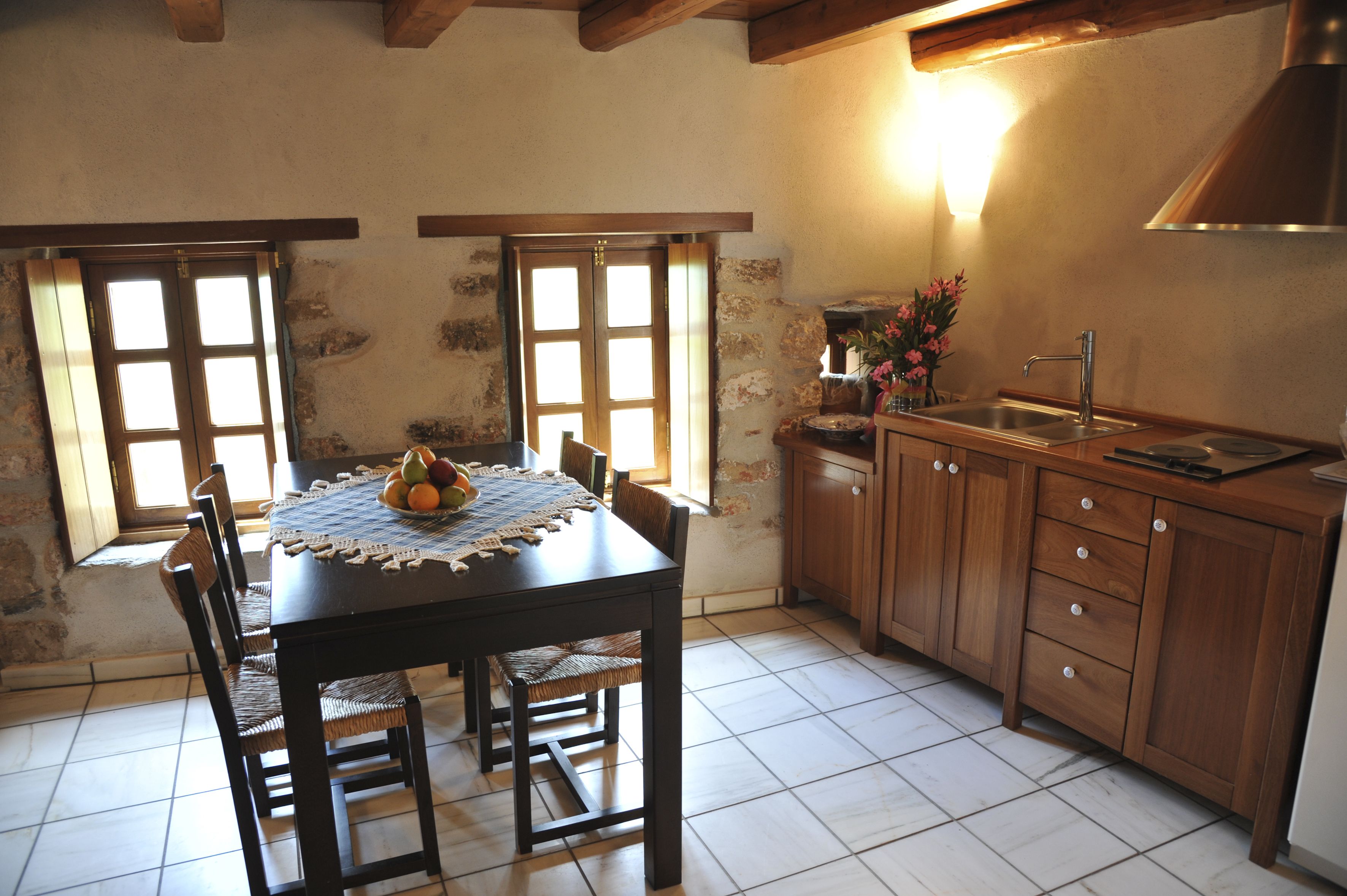 A kitchen with a wooden table, chairs, a sink, and cabinets.