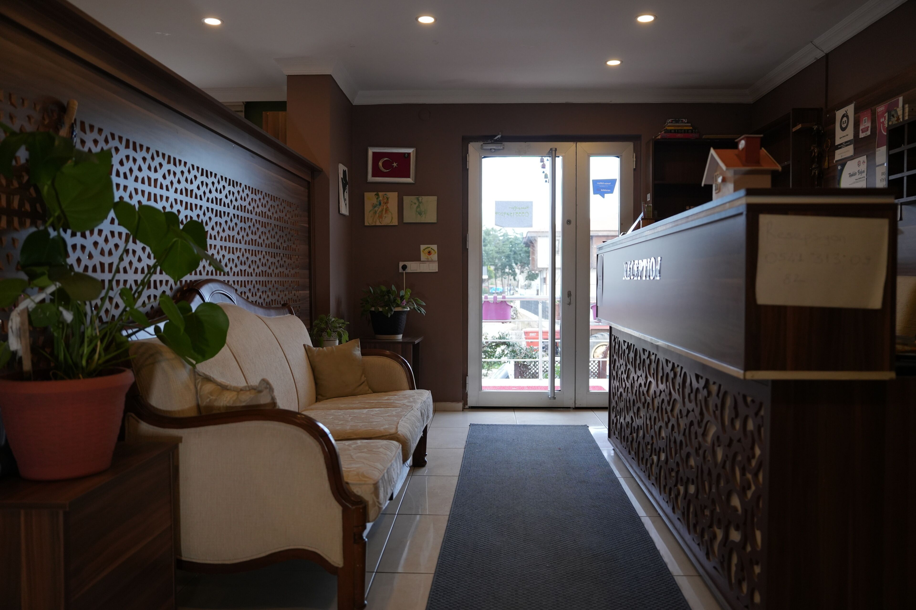 A reception area with a reception desk, a sofa, a potted plant, and a decorative wall.