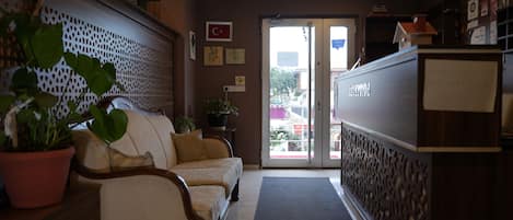 A reception area with a reception desk, a sofa, a potted plant, and a decorative wall.