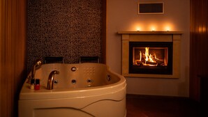 A bathroom with a freestanding bathtub, a fireplace, and a textured wall. - Defne Hotel (Sile)
