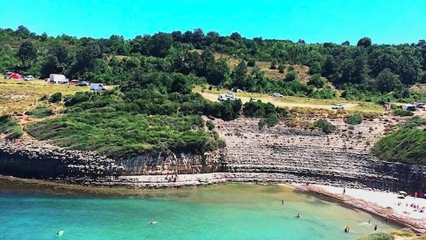 A coastal area with a beach, rocky cliffs, and a road with vehicles. - Defne Hotel (Sile)