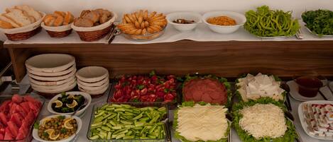 A buffet with various food items including bread, vegetables, and salads.