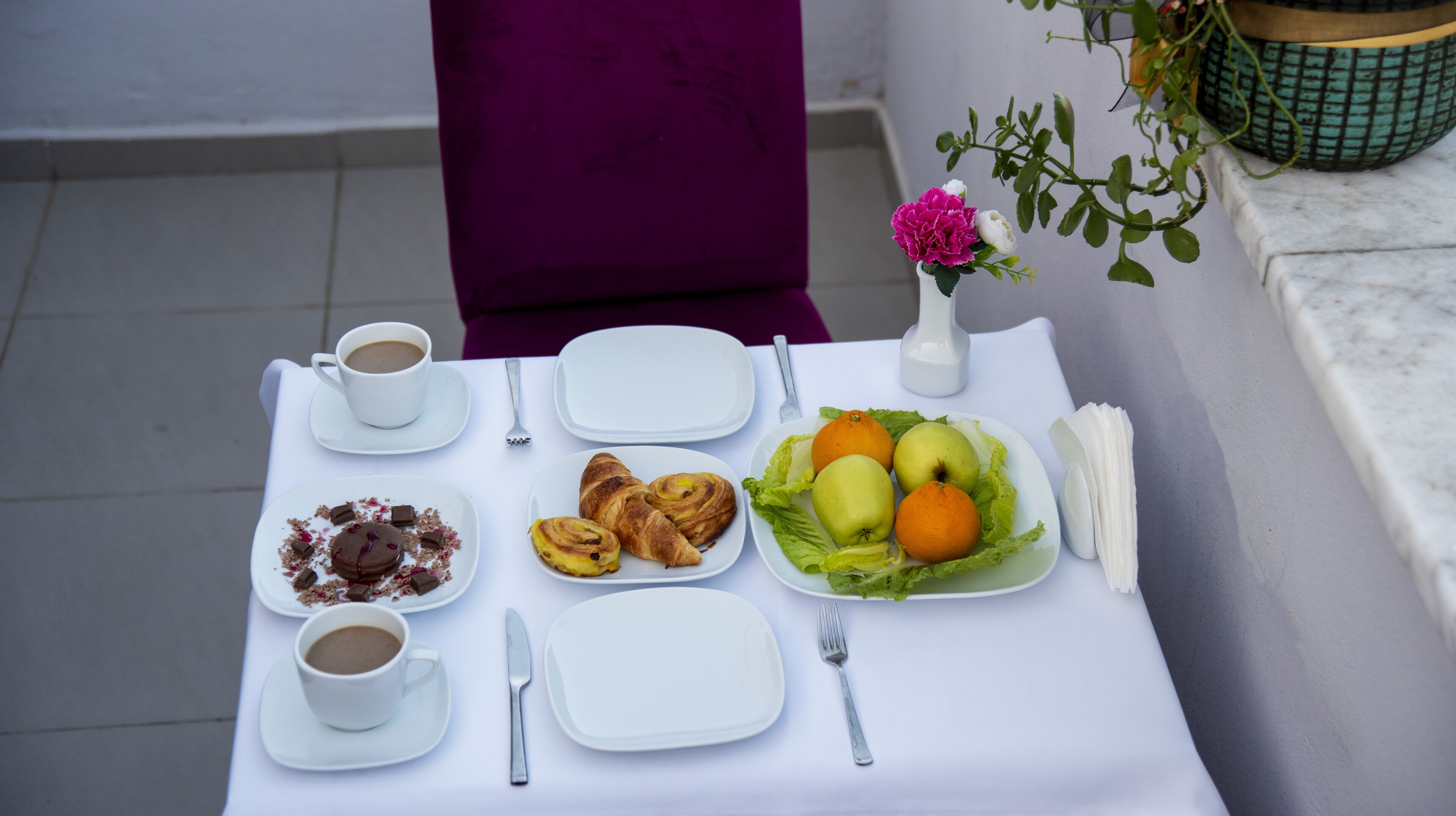 Una mesa dispuesta con alimentos para el desayuno, incluyendo croissants, fruta y café.