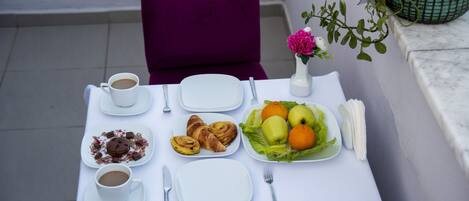 Una mesa dispuesta con alimentos para el desayuno, incluyendo croissants, fruta y café.