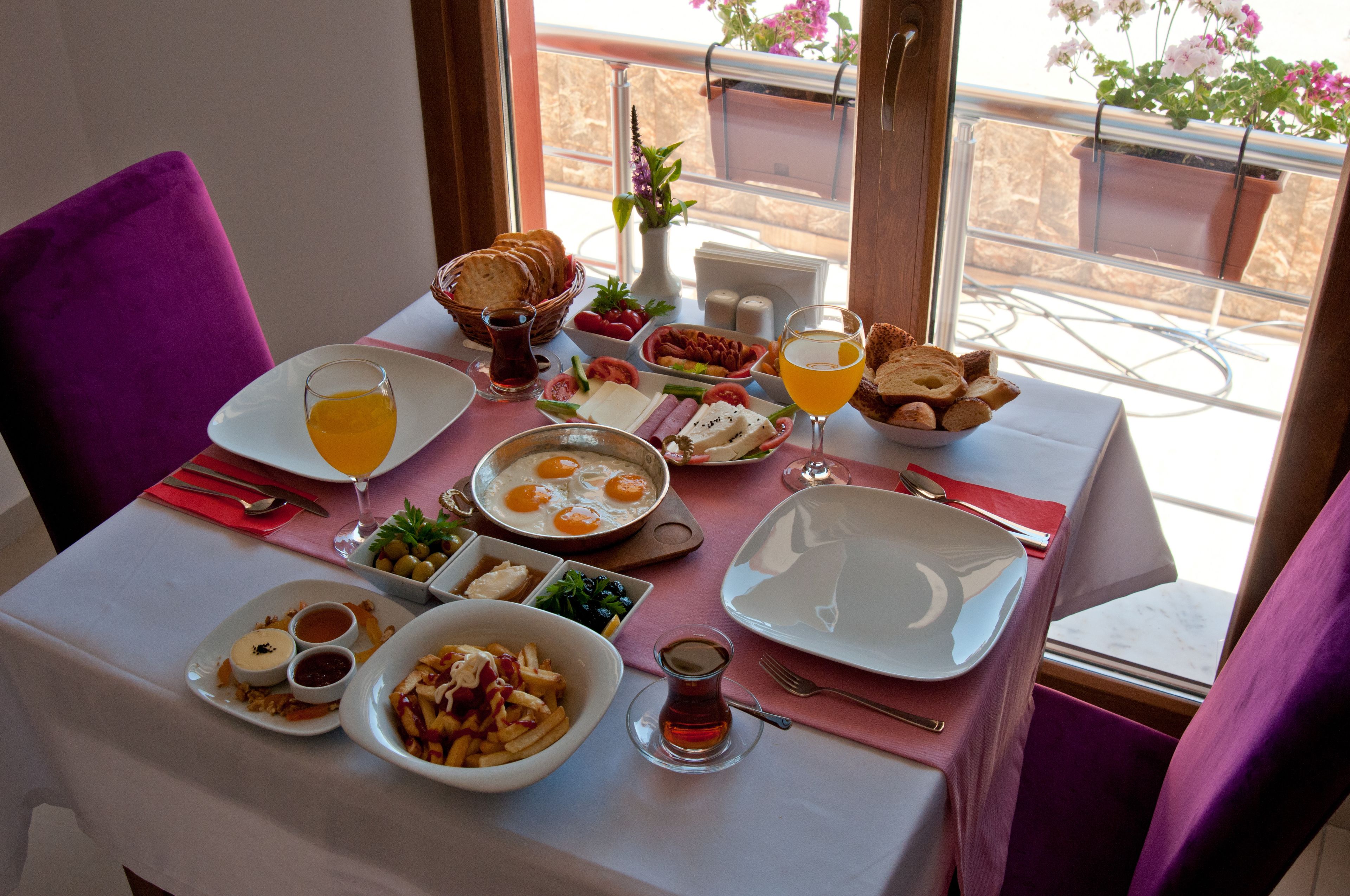 Une table de petit-déjeuner avec divers plats, notamment des œufs, des toasts et des fruits.