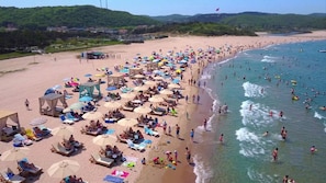 A beach with sun loungers, umbrellas, and people swimming. - Defne Hotel (Sile)