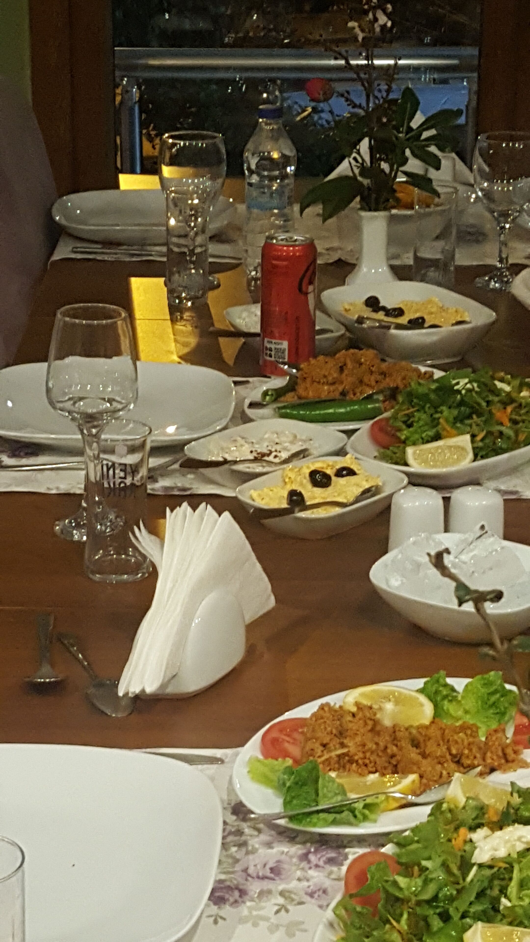 Una mesa de comedor servida con diferentes platos, incluyendo ensaladas, arroz y una lata de refresco.