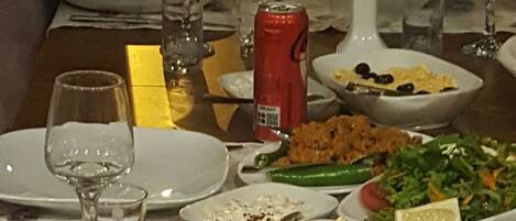 Una mesa de comedor servida con diferentes platos, incluyendo ensaladas, arroz y una lata de refresco.
