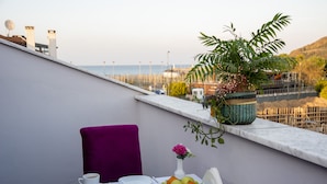 A balcony with a table set for breakfast, including plates, cups, and a potted plant. - Defne Hotel (Sile)