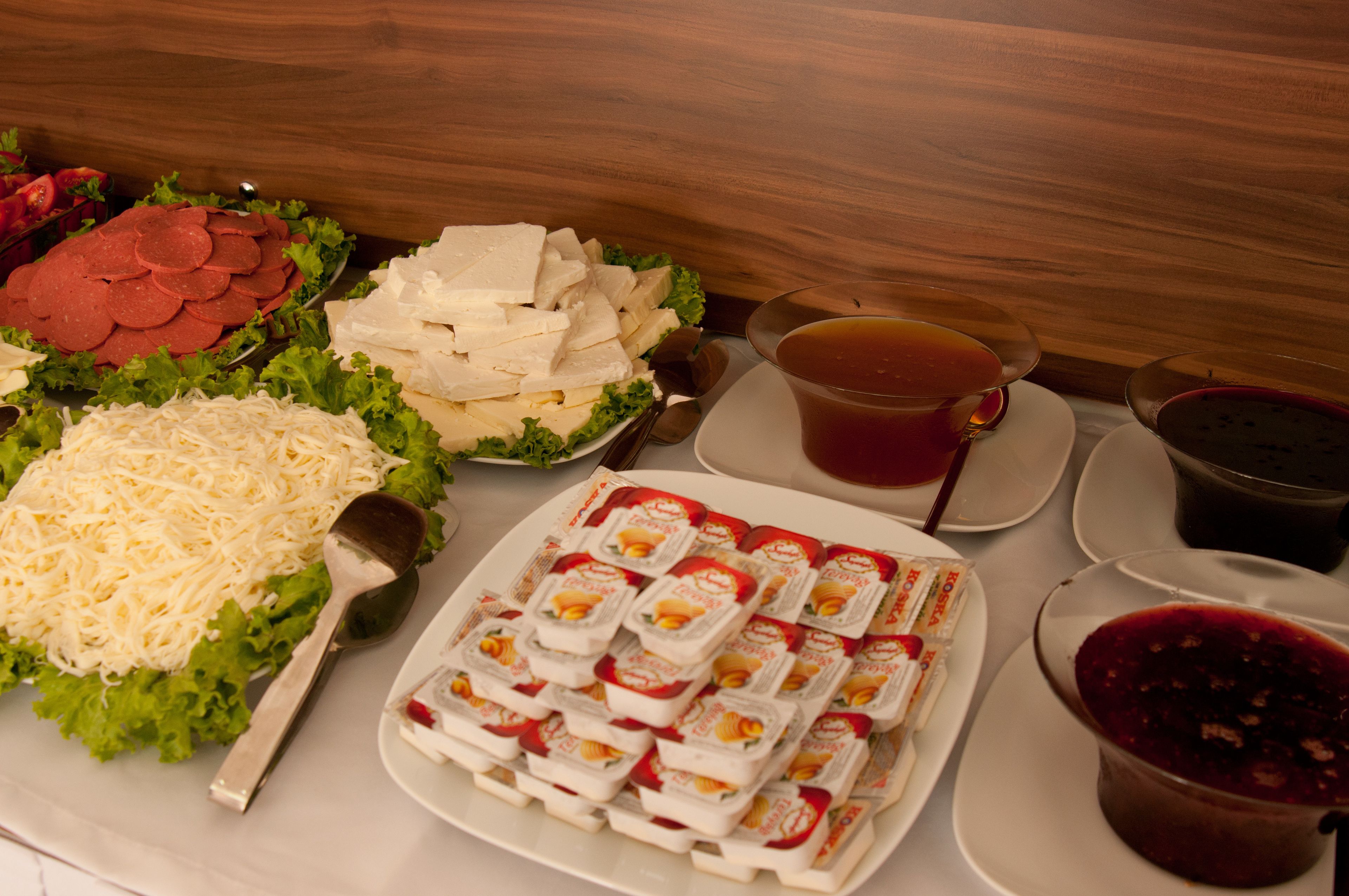 Una mesa con diferentes alimentos, incluyendo carne en rodajas, queso y salsas.