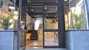 A modern interior with a reception desk, staircase, and potted plants. - Quartier Bilbao Hostel (Bilbao)