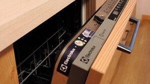 A kitchen with a dishwasher integrated into a wooden cabinet, a stainless steel sink, and a modern faucet. - Meuble Cima Bianca Garni (Bormio)