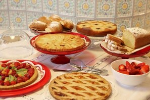 A variety of baked goods including pies, a loaf of bread, and pastries on a table with a tiled backsplash. - Meuble Cima Bianca Garni (Bormio)