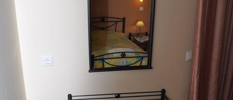 Une pièce comprenant un lit, un bureau, une chaise, un miroir et une lampe.
