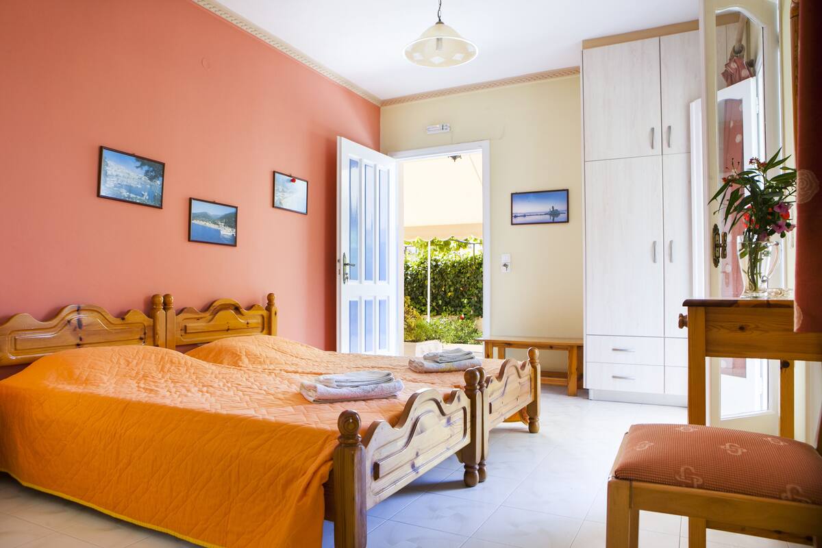 Ein Schlafzimmer mit Bett, Stuhl, Kleiderschrank und einer Tür, die auf einen Balkon führt.