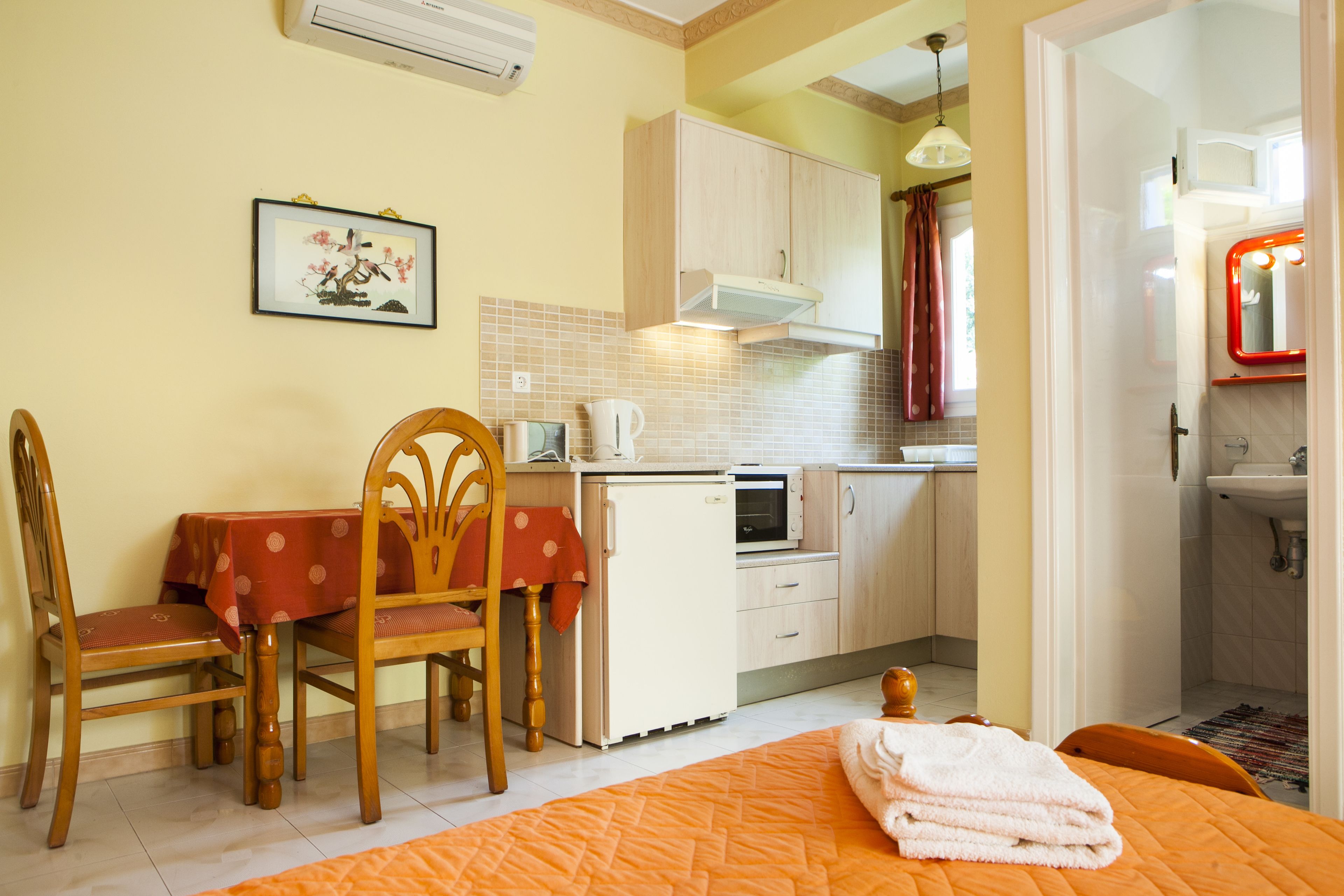 Una habitación compacta con cama, una mesa de comedor con sillas, una kitchenette y un baño.