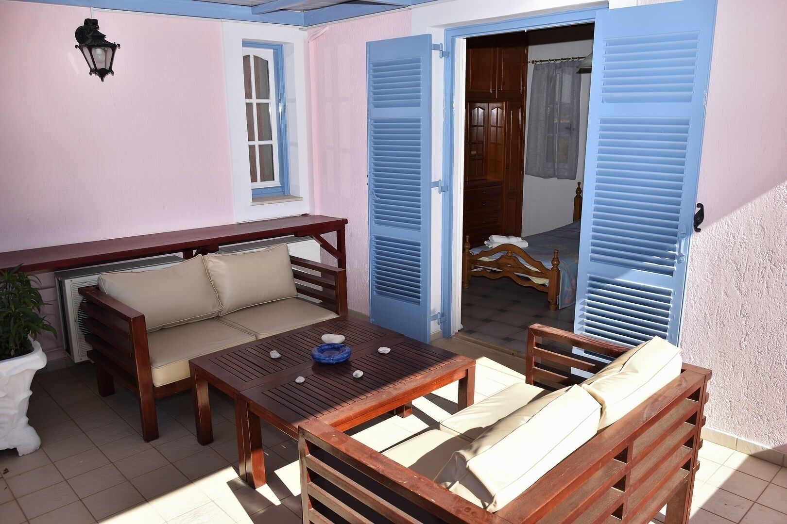 A cozy patio area with a wooden table, cushioned seating, and a potted plant.