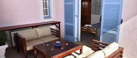 A cozy patio area with a wooden table, cushioned seating, and a potted plant.