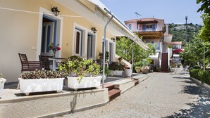 A street with buildings, outdoor seating, and potted plants. - Tzivras Villa & Apartments (Kefalonia)