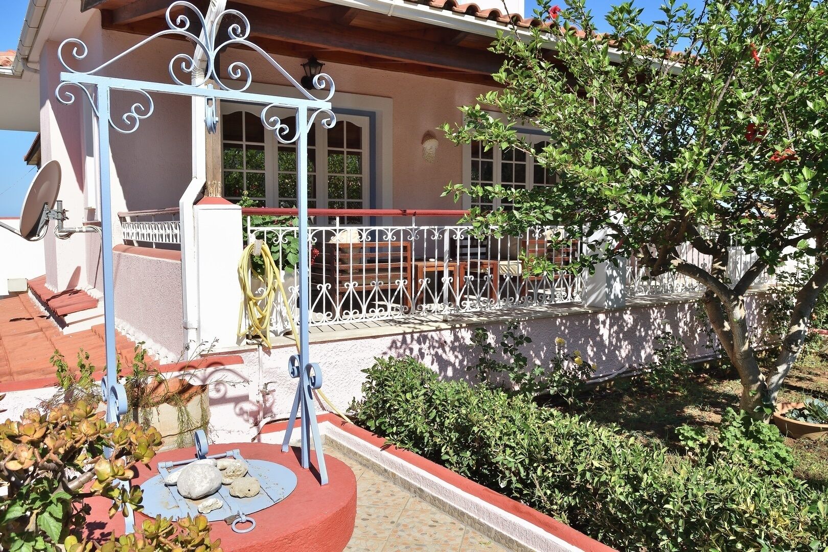 Una casa con jardín, una reja metálica y una cerca roja y blanca.