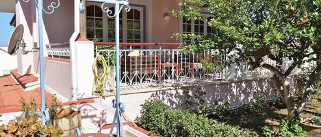 Una casa con jardín, una reja metálica y una cerca roja y blanca.