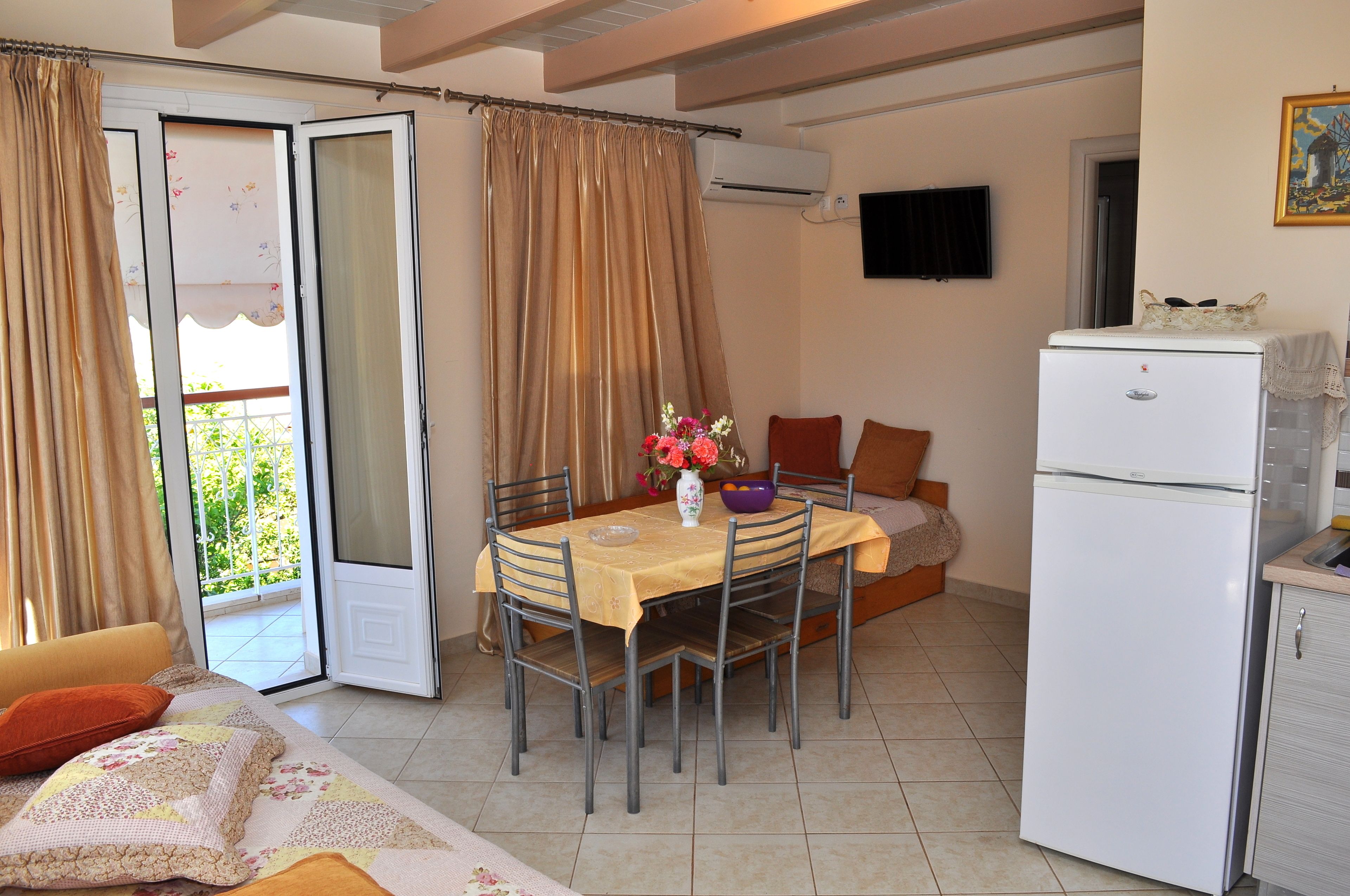 Un comedor con una mesa dispuesta para cuatro personas, un refrigerador y un sofá al fondo.