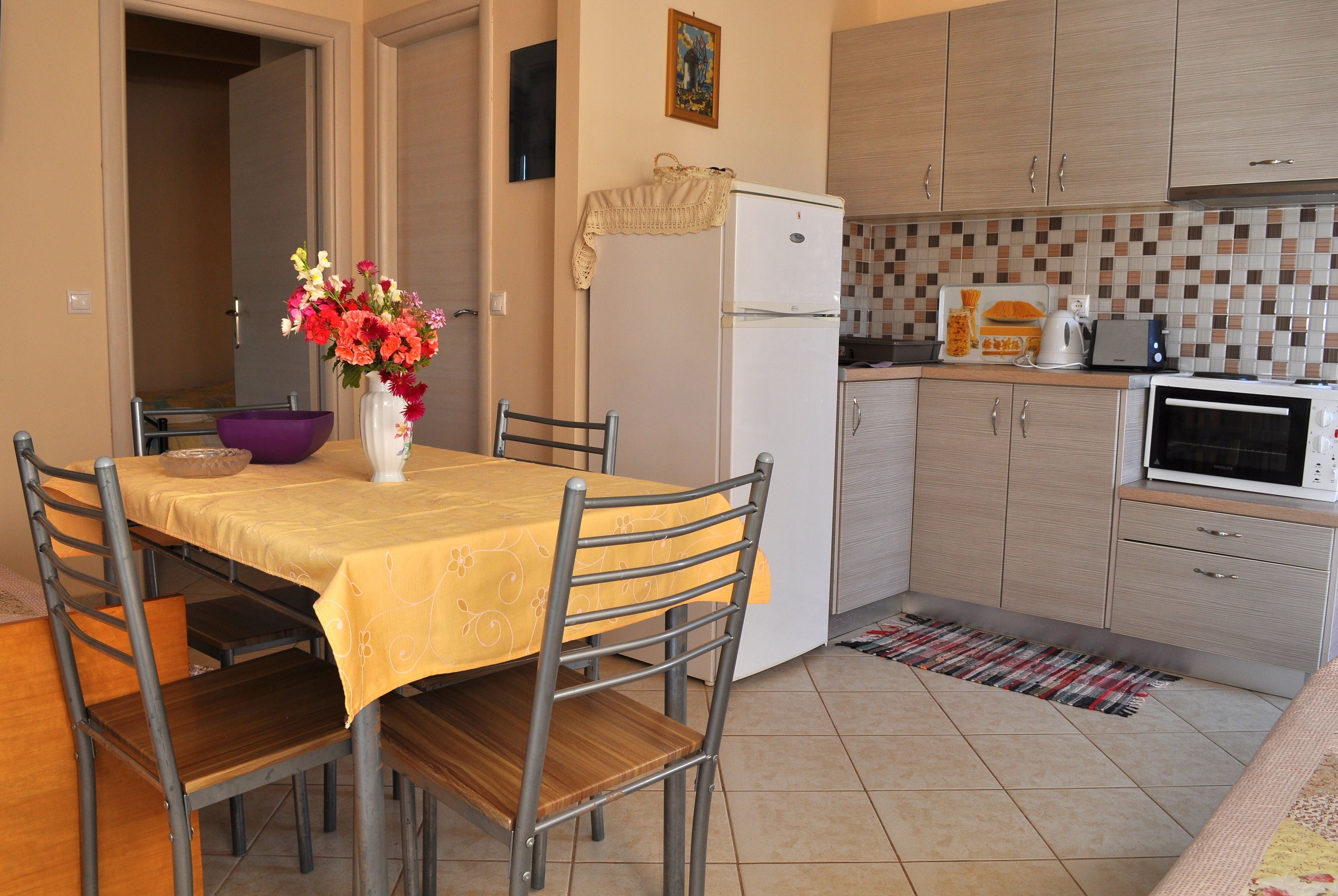 Una cocina compacta con comedor, que incluye un refrigerador, microondas y un reverso de azulejos.