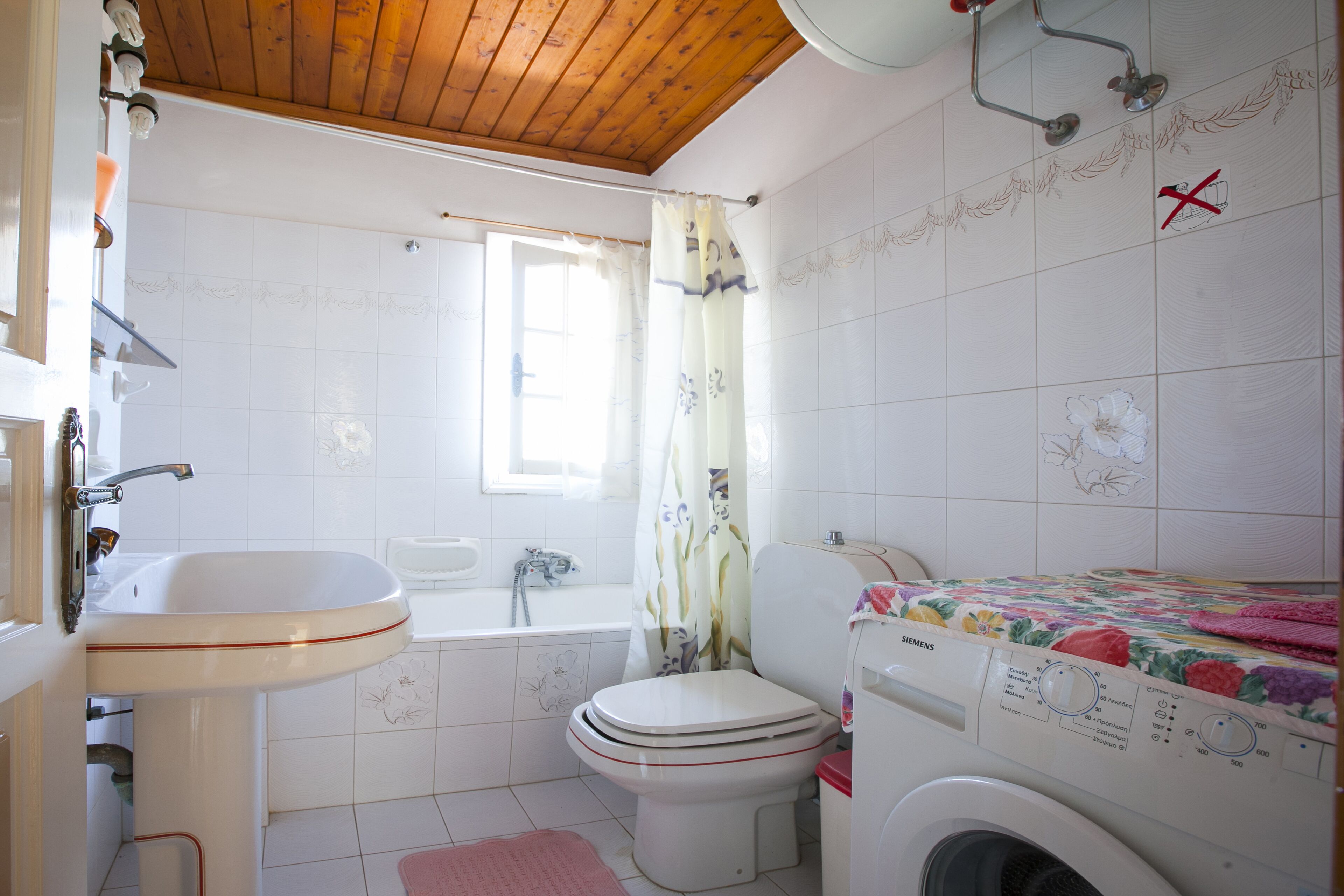 Casa de banho com lavatório, sanita e máquina de lavar roupa.