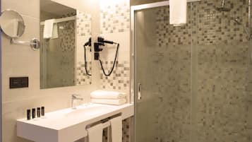 Un baño moderno con ducha de vidrio, lavamanos blanco y espejo grande.
