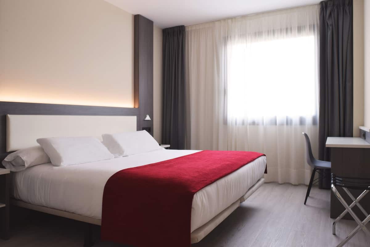 Una habitación de hotel con una cama, un escritorio y una silla.