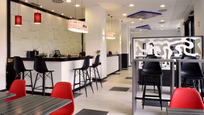 A modern restaurant with a bar area, black and red chairs, and pendant lighting. - Hotel New Bilbao Airport (Derio)