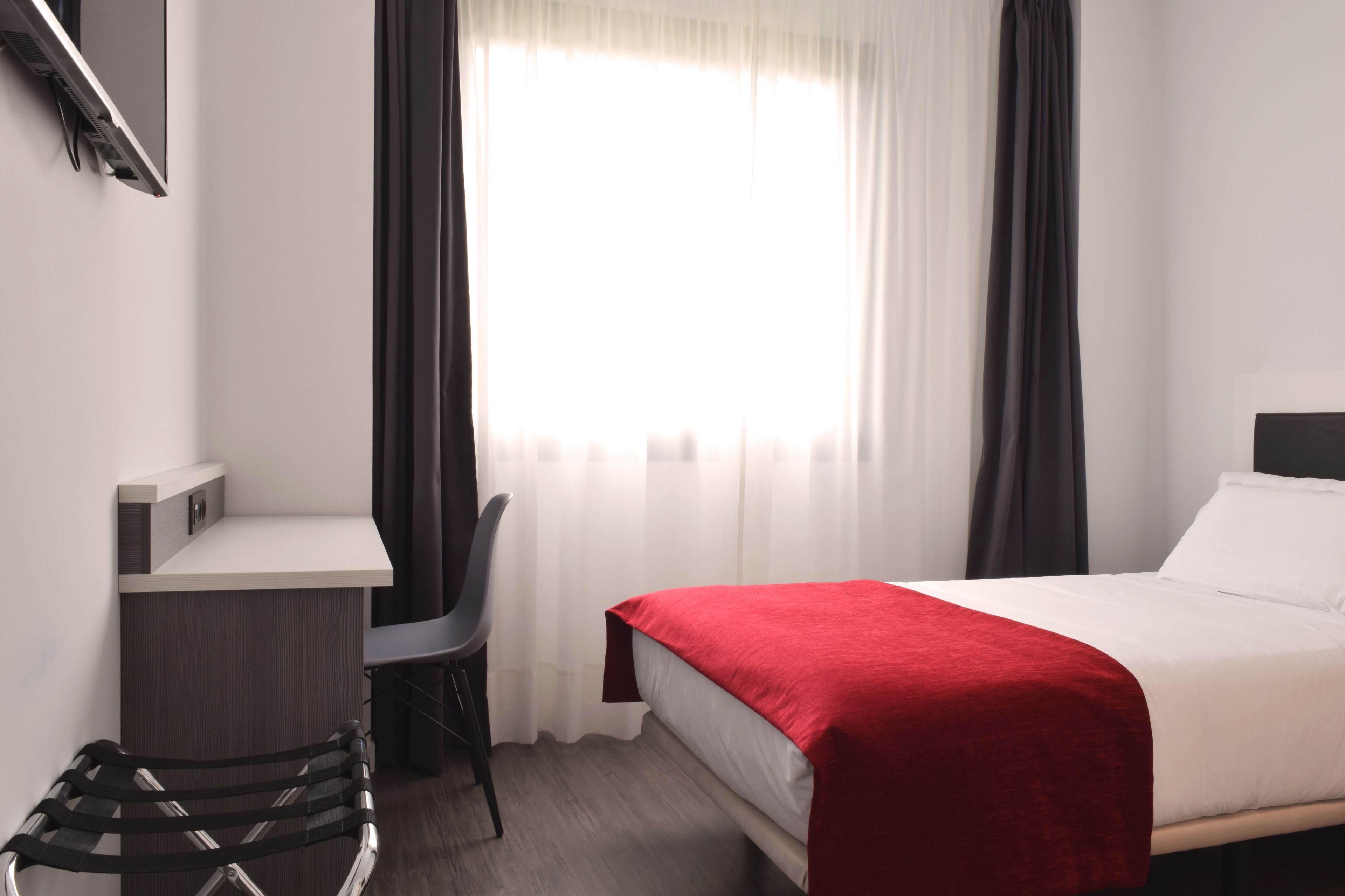 A hotel room with a bed, a desk, and a chair.