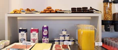 A breakfast buffet with various food items, including pastries, meats, cheeses, and juices.
