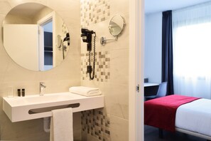 A hotel bathroom with a sink, mirror, and hairdryer. - Hotel New Bilbao Airport (Derio)