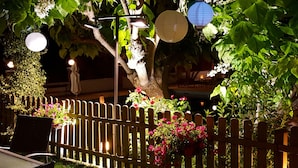 Una cerca de madera con un jardín, que incluye flores y un árbol.