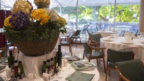 Un comedor con mesas dispuestas para una comida, un centro de flores y varias botellas y copas sobre las mesas.