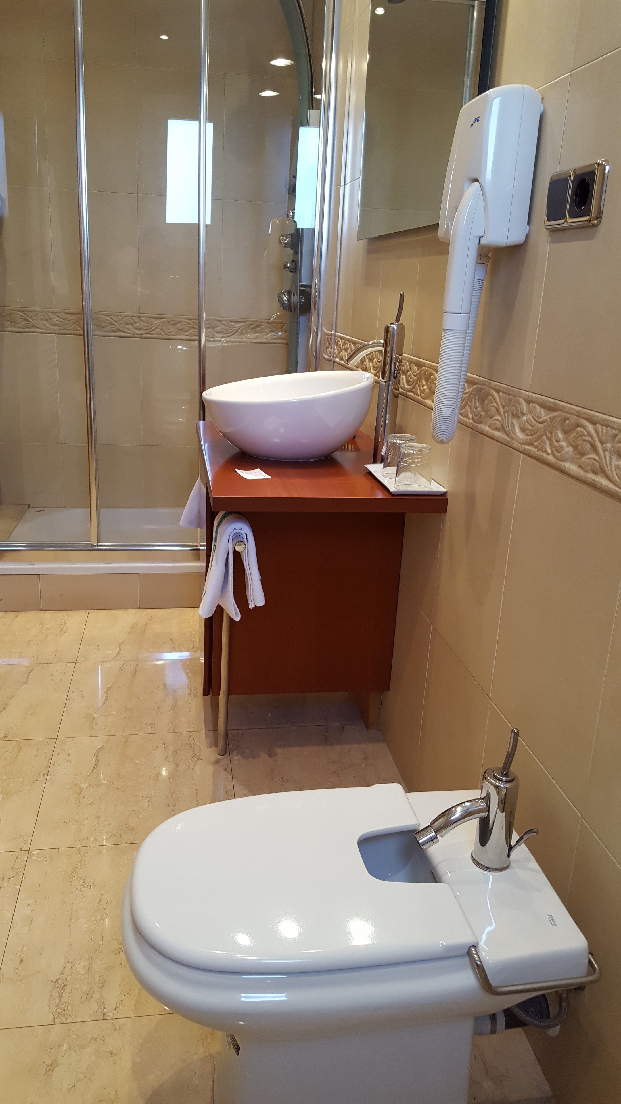A bathroom with a white toilet, a sink with a white basin, and a glass shower enclosure.