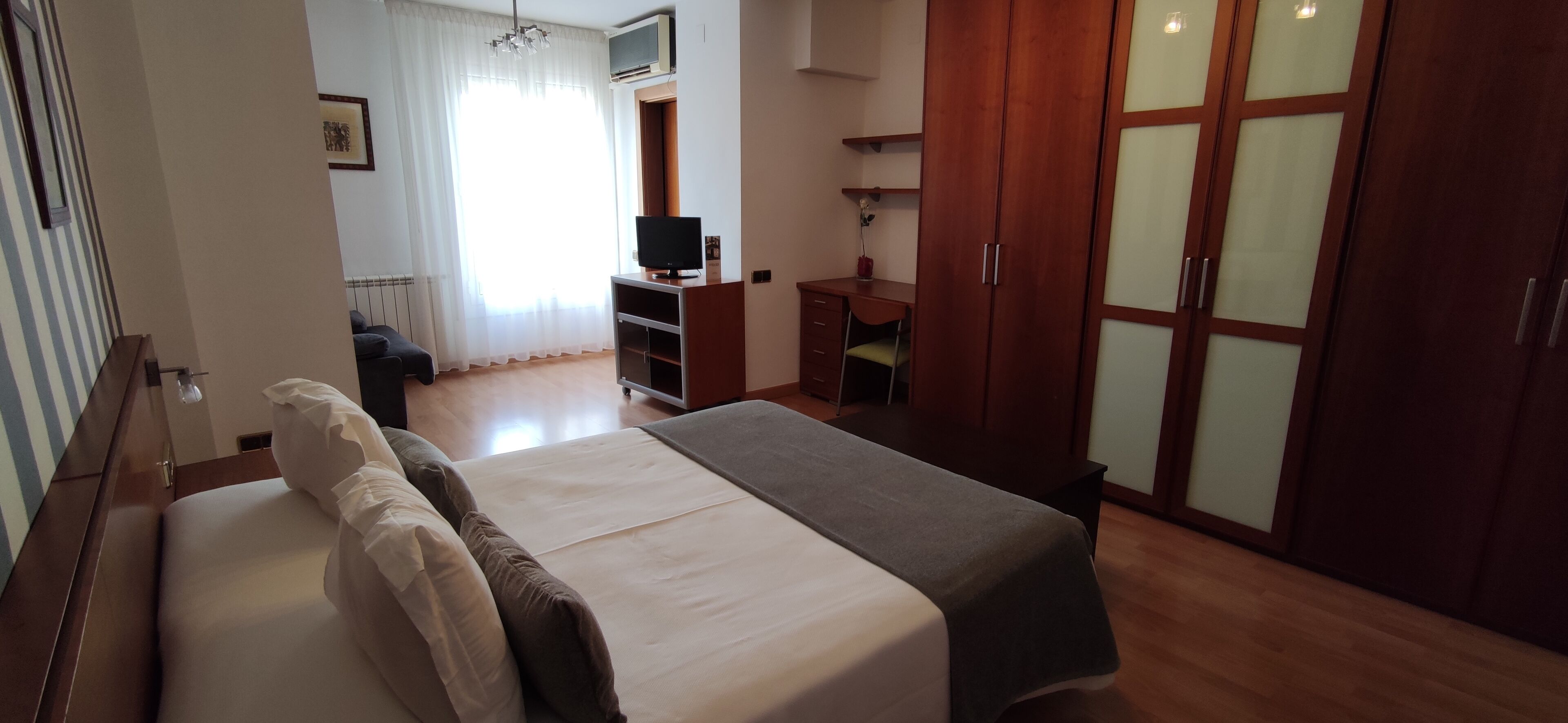 Ein Schlafzimmer mit Bett, Schreibtisch, Kleiderschrank und Fernseher.