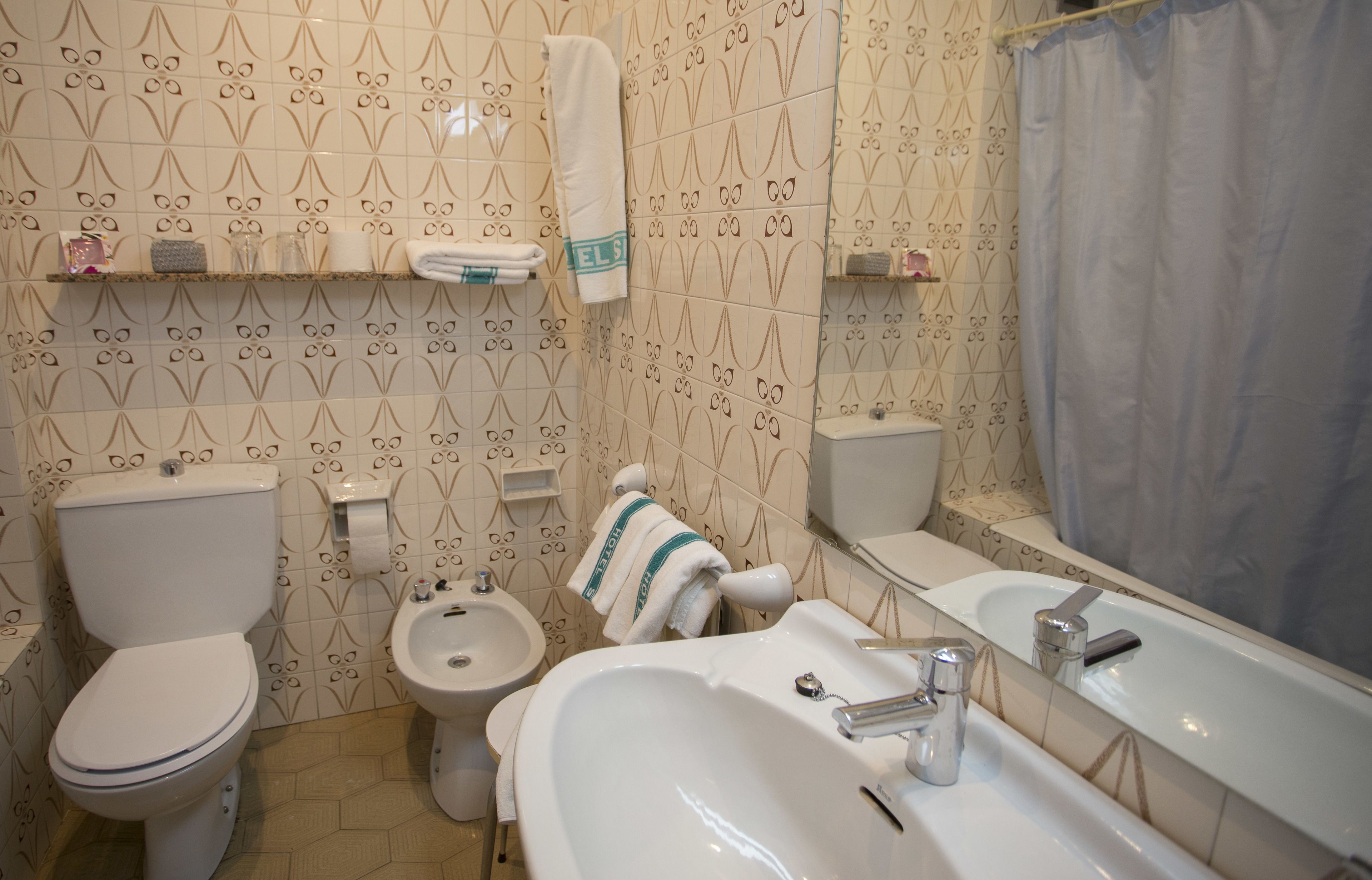 A bathroom with a toilet, bidet, sink, and mirror.