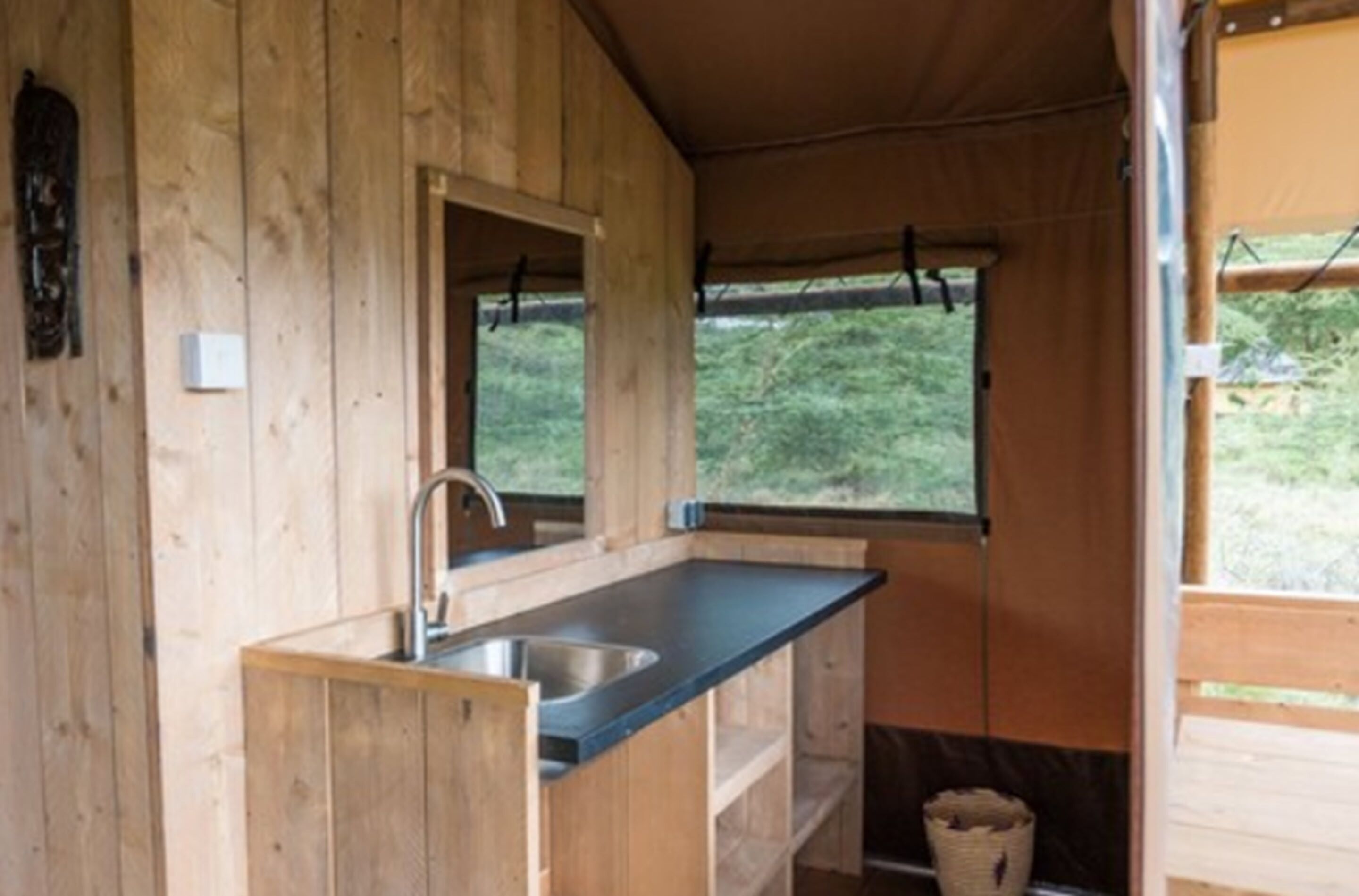 Uma cabana de madeira compacta com cozinha compacta, incluindo pia e janela.