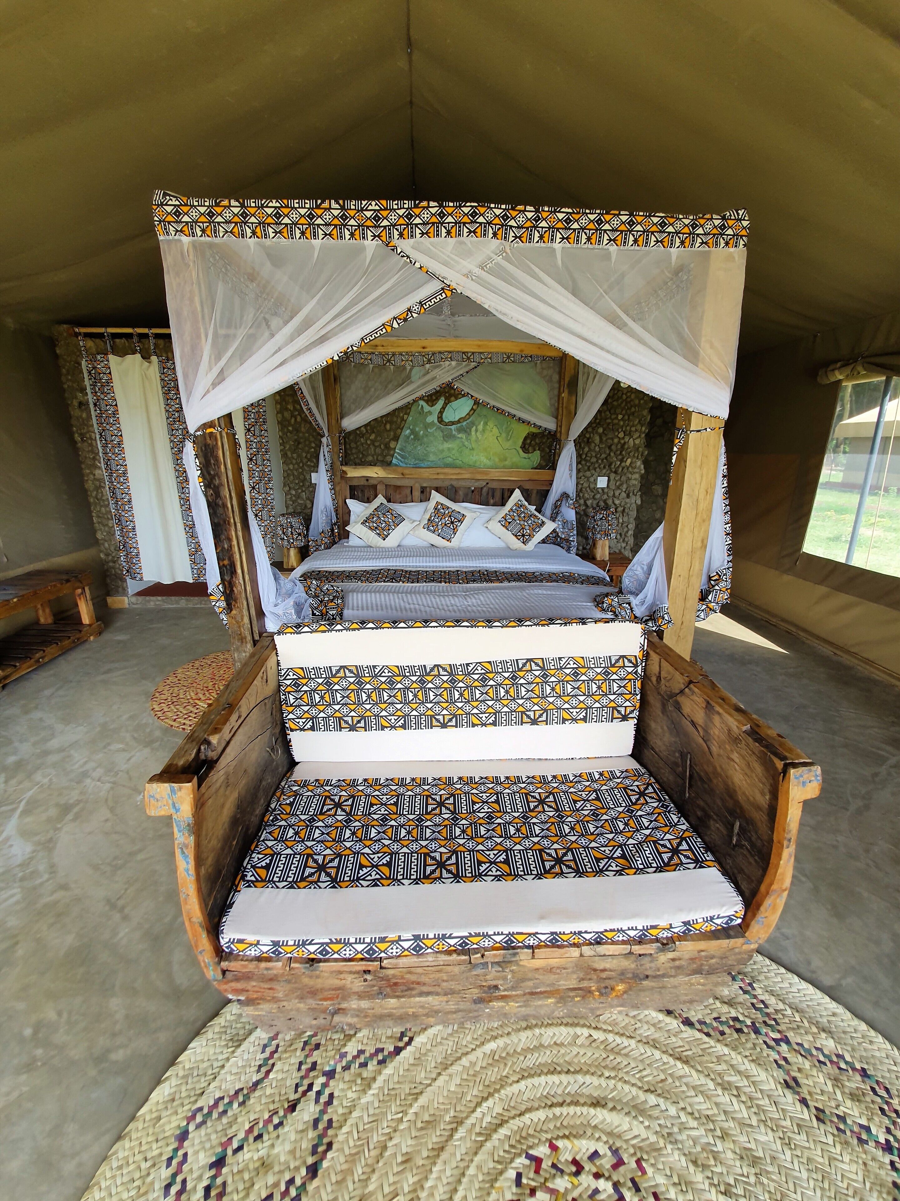 Un lit à baldaquin avec une literie à motifs, un tapis tissé et un mur de pierre en arrière-plan.