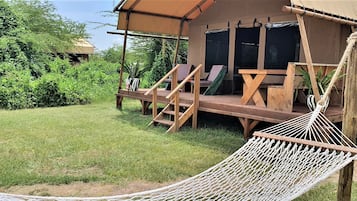 A wooden deck with a hammock, a wooden bench, and a small table.