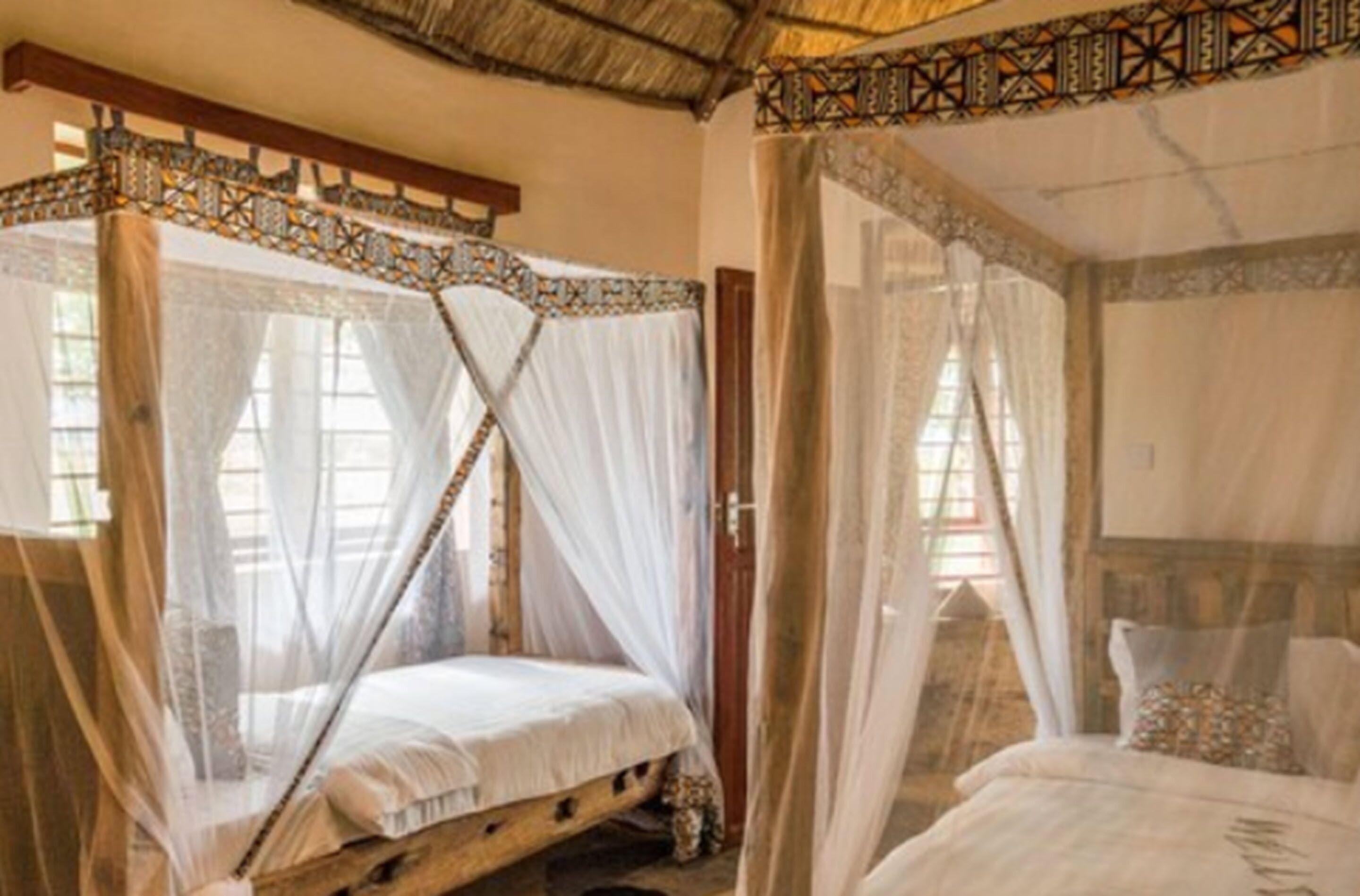 A traditional room with a bed under a canopy, a wooden headboard, and a window with a view.