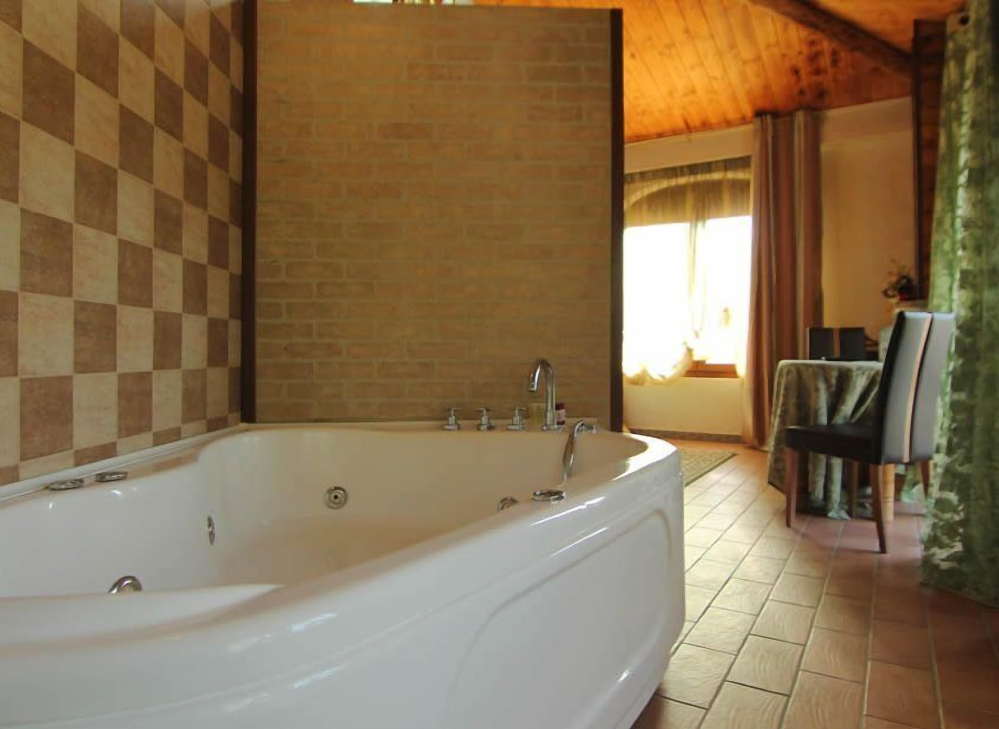 Ein Badezimmer mit einer großen Badewanne, Schachbrettfliesen an der Wand und einer Holzbalkendecke.