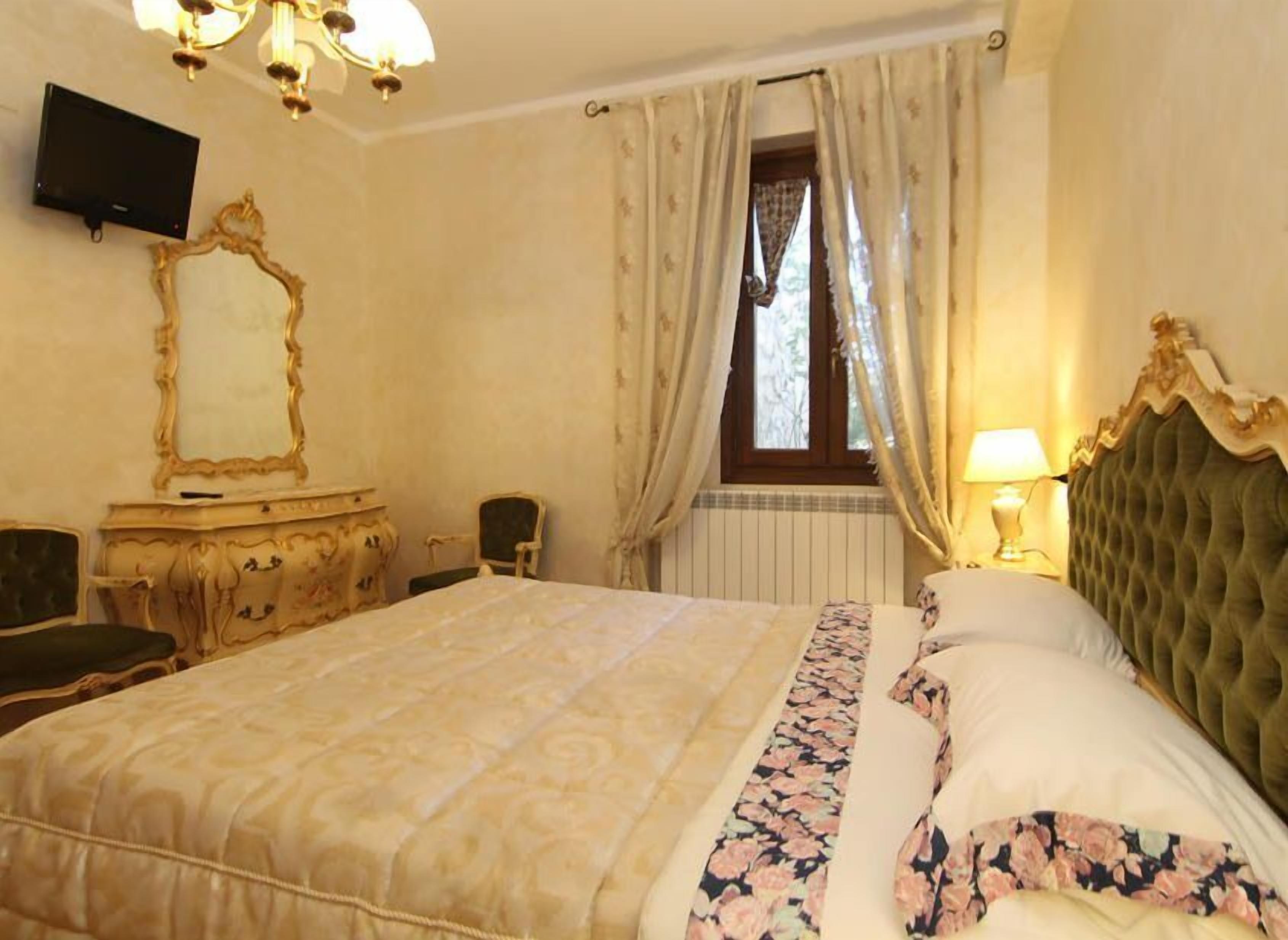 A hotel room with a large bed, a dresser, a television, and a window with curtains.