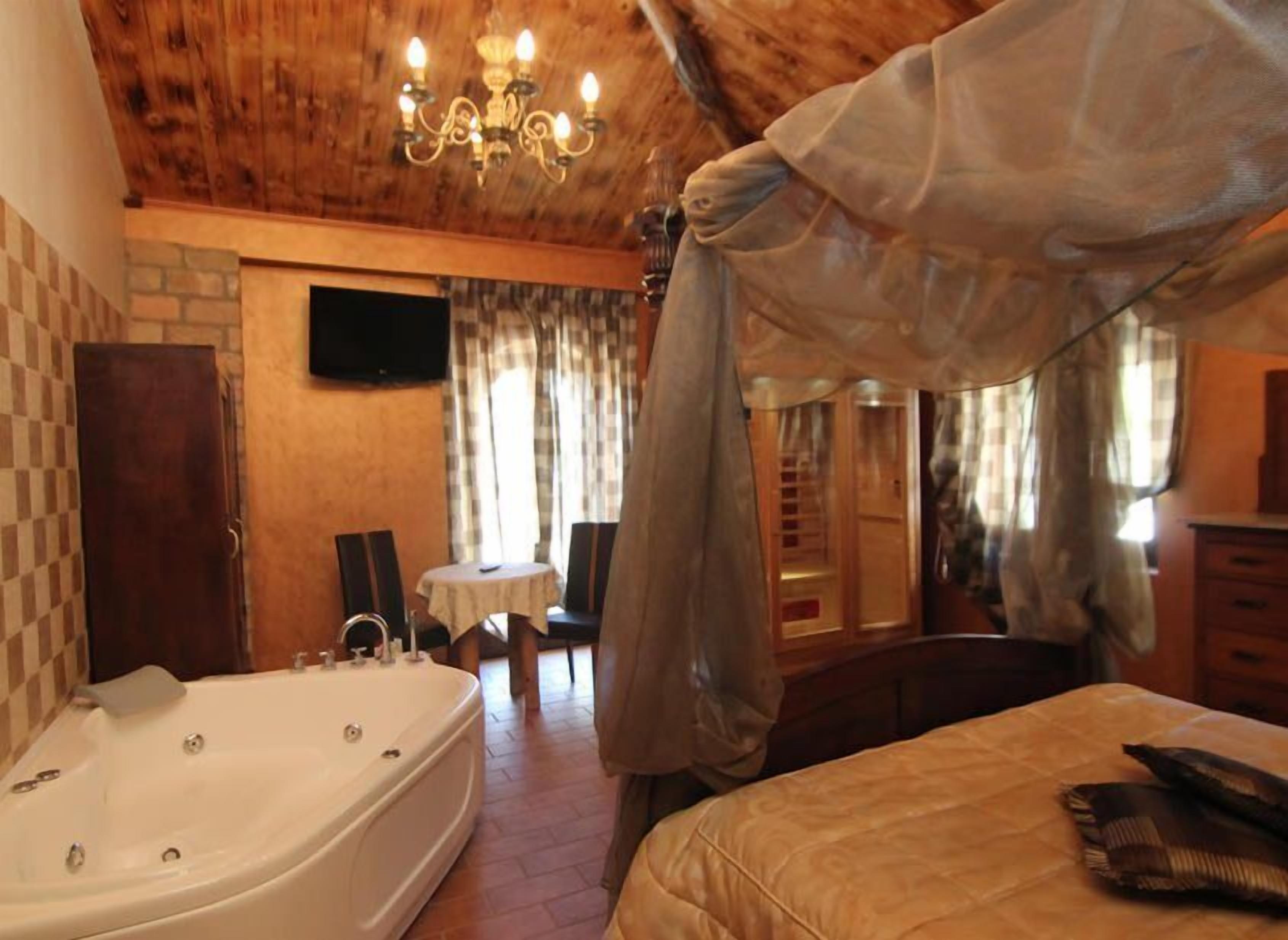 Une chambre avec une grande baignoire, un lit, un lustre et un coin repas comprenant une table et des chaises.