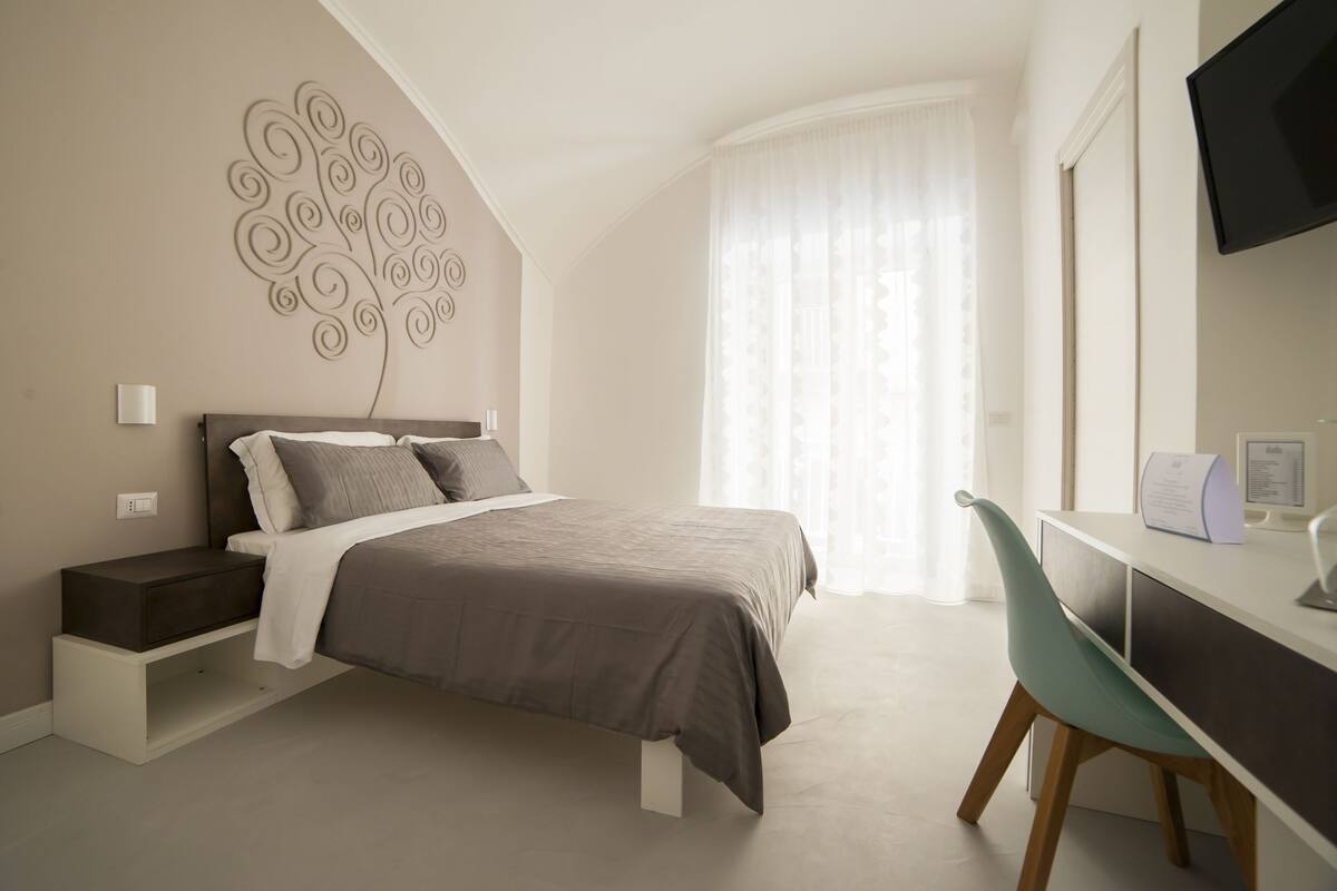 A bedroom with a bed, bedside table, and a desk with a chair.