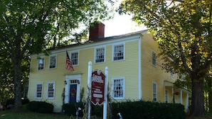 A yellow colonial-style building with a sign indicating it is the Colonel Spencer Inn, offering bed and breakfast services. - Colonel Spencer Inn (Campton)