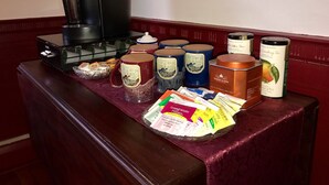 A coffee station with a coffee maker, various tea tins, and tea bags on a wooden counter. - Colonel Spencer Inn (Campton)